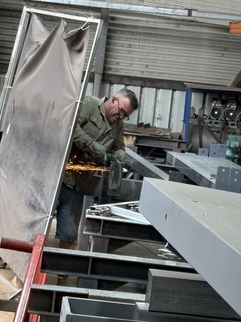 Marshall Steel fabrication — grinding steel behind the welding curtain at Burleigh Heads